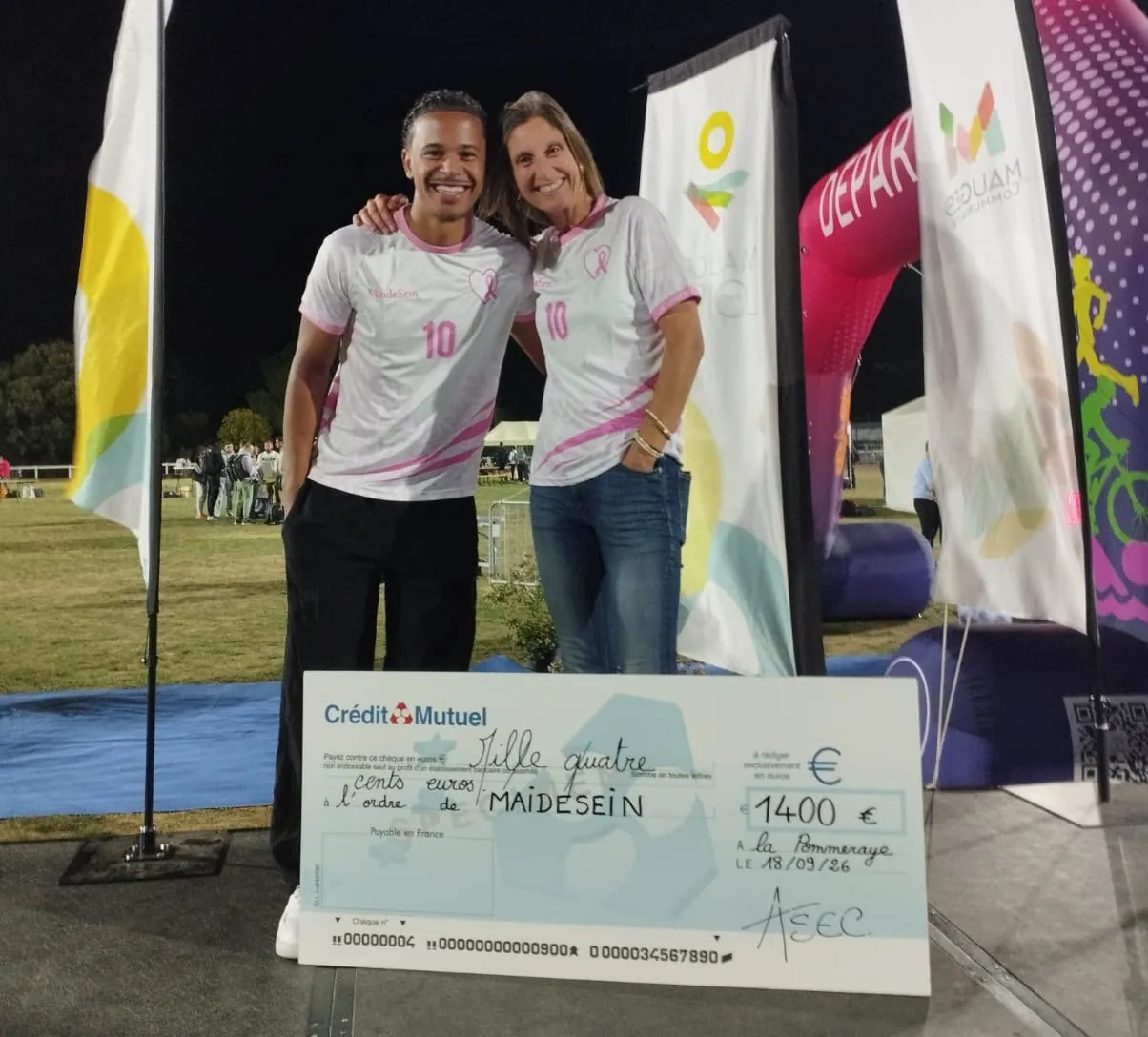 Deux personnes en maillot MAIDESEIN posent, souriantes, derrière un chèque géant de 1 400 € à l’ordre de MAIDESEIN